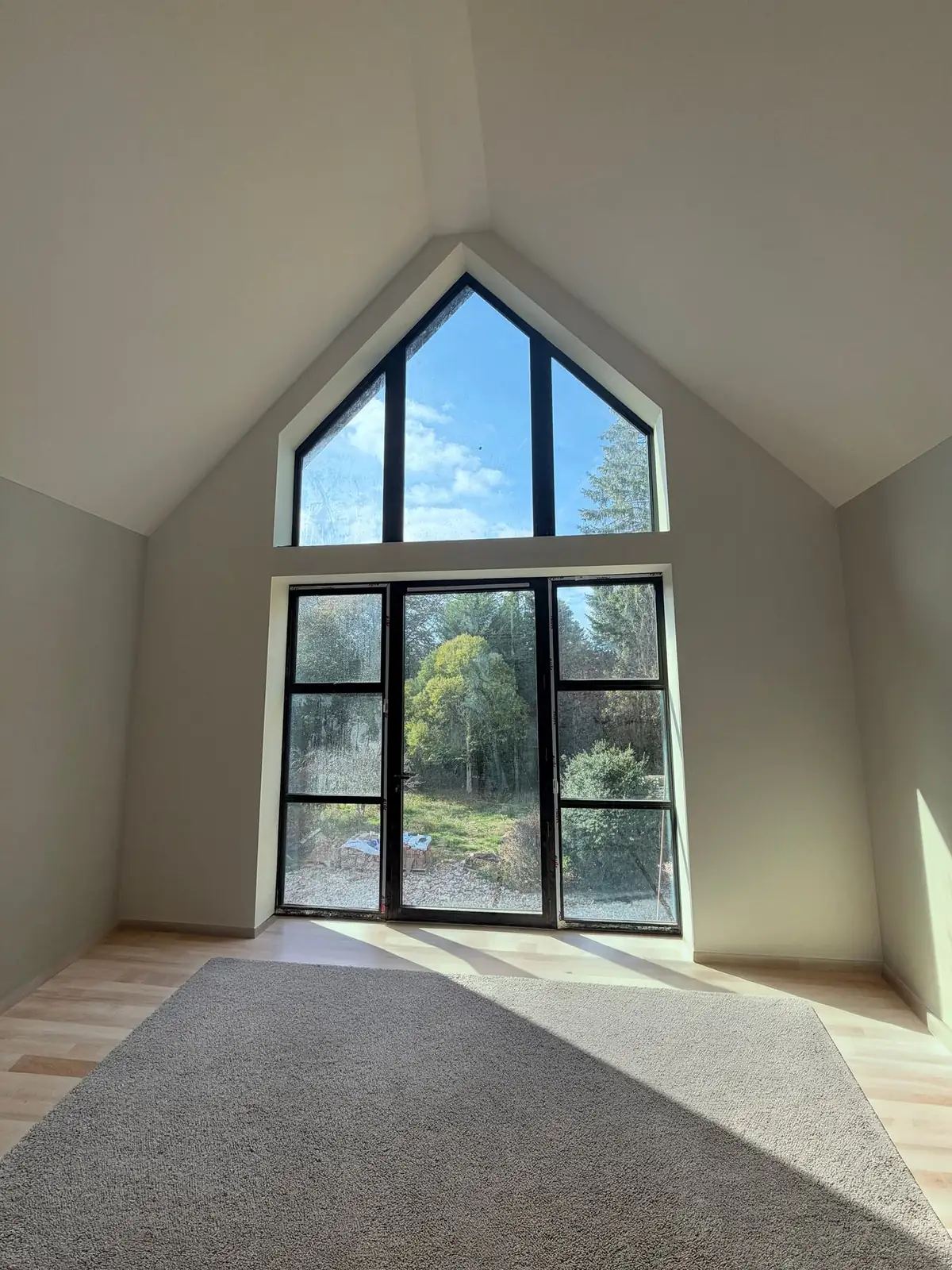 Vaulted new-build living room with a large gable window, freshly decorated